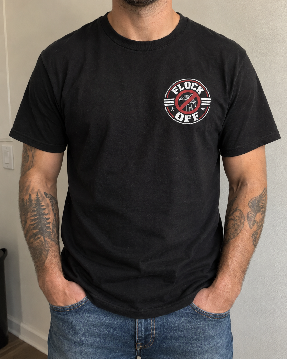 Man wearing the black Flock Off Tee with jeans, showing the relaxed everyday fit and the small left-chest badge
